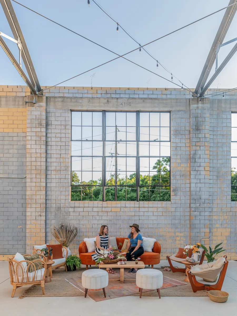 Two guests chat on a rust velvet sofa in the open-air Social Hall lounge