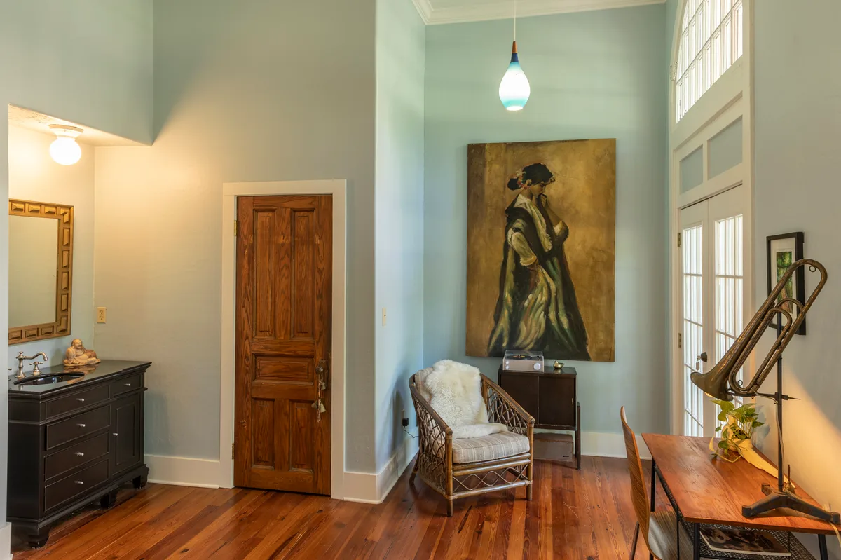Schoolhouse sitting corner with a tall portrait, rattan chair and vintage record player cabinet