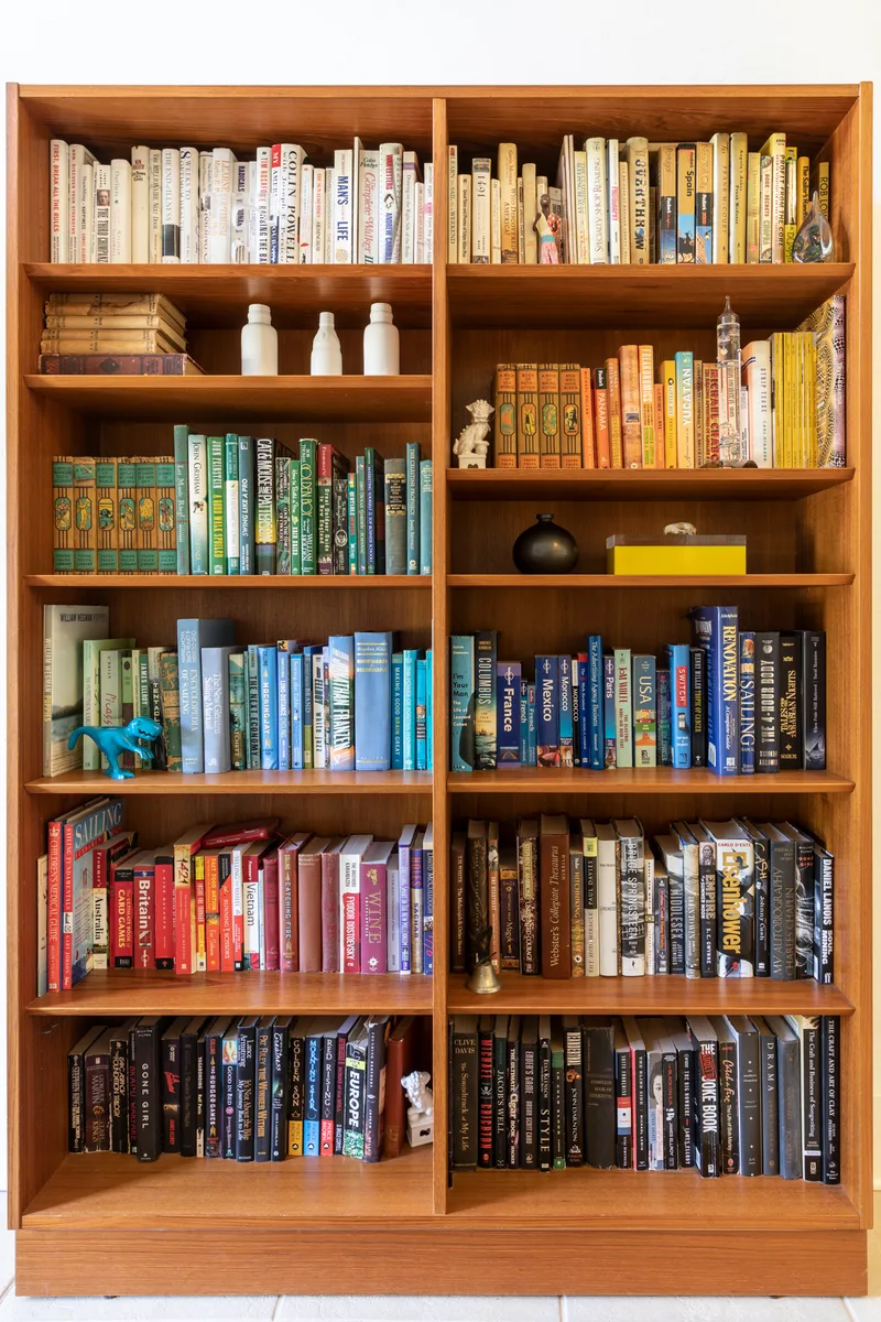 School Library's teak shelves packed with colour-sorted books, pottery and a brass bell