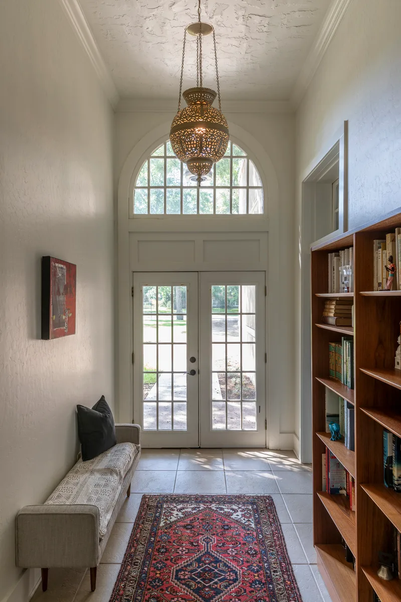 Narrow entry hall with arched fanlight, pierced brass lantern and red Persian runner