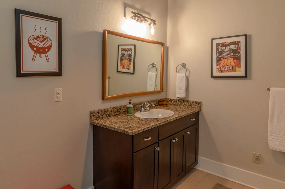 Guest bathroom vanity with granite top, framed letterpress posters and white towels