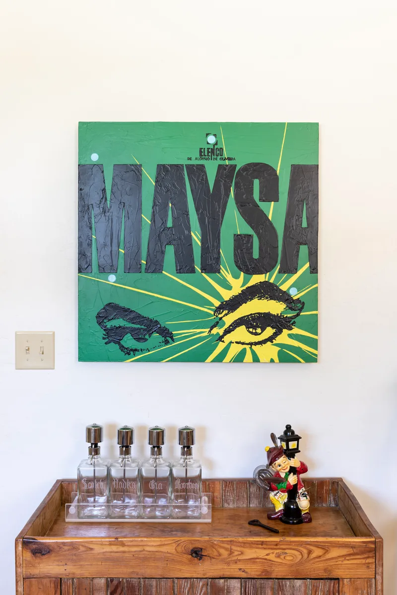 Green pop-art canvas with bold lettering above a rustic wood bar and glass decanters