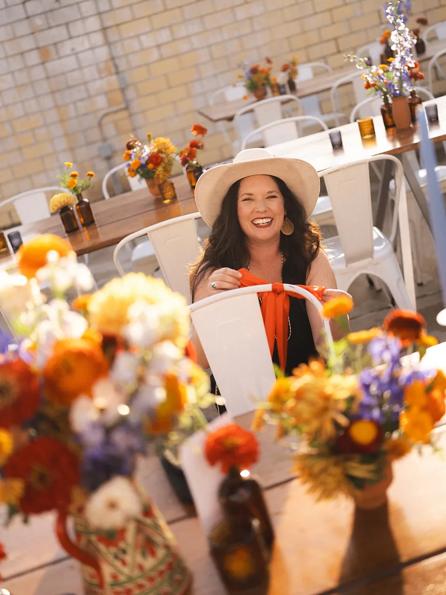 Smiling guest in a white cowboy hat at a Social Hall reception table set with bright wildflower arrangements