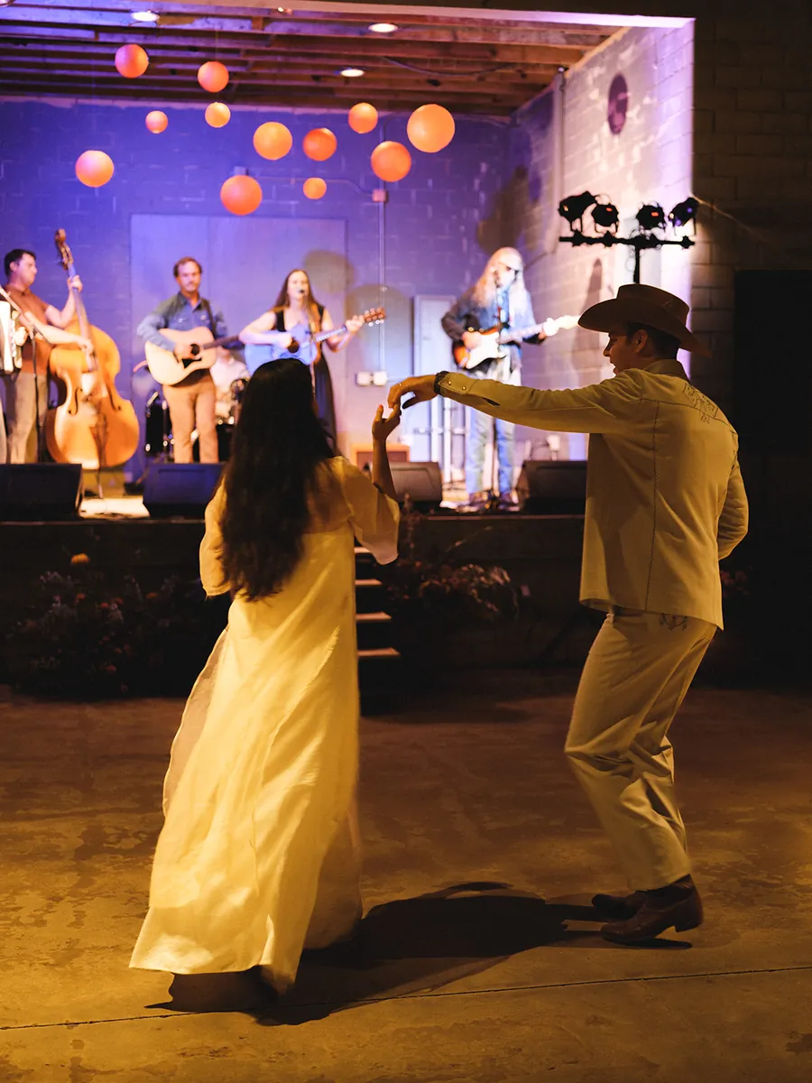 Couple dancing in front of a live band on stage, orange paper lanterns hanging overhead